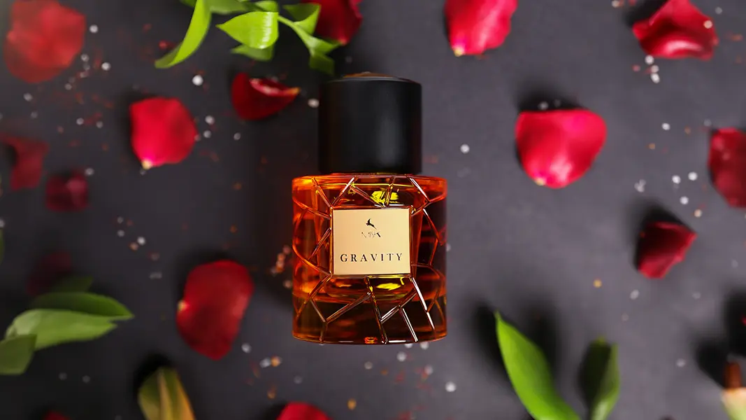 Gravity perfume bottle photographed from above among scattered rose petals